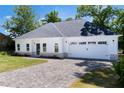 Charming single-story home with a white exterior, a gray roof, and a paver driveway at 614 Glendale Rd, Scottdale, GA 30079