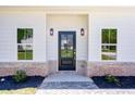 Close-up of a modern front door flanked by elegant sconces and trimmed by light brick at 614 Glendale Rd, Scottdale, GA 30079