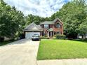 Charming brick home with a well-manicured lawn and a two-car garage and lush front yard at 627 Arbour Way, Suwanee, GA 30024