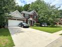 Charming brick home with a two-car garage and lush, green front lawn with mature trees at 627 Arbour Way, Suwanee, GA 30024