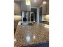 Close-up of the kitchen island featuring granite countertops, stainless steel faucet, and gray cabinetry at 3677 Malachi Way Way, Loganville, GA 30052