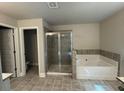 Modern bathroom featuring a separate shower, soaking tub, and neutral-toned tiles for a clean aesthetic at 338 Cherryhill Ln, Woodstock, GA 30188