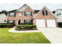 Charming two-story brick home showcasing a two-car garage and manicured landscaping at 665 Roxford Ln, Buford, GA 30518