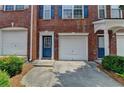 Brick townhome exterior featuring attached garage, a blue door and fresh landscaping at 3187 Mill Springs Cir, Buford, GA 30519