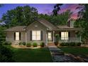 Inviting single-story home with a well-manicured lawn and an inviting front porch at twilight at 6960 Worley Rd, Cumming, GA 30028