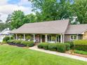 Beautiful single-story home featuring a cozy porch, lush lawn, and mature landscaping at 12162 Mountain Laurel Dr, Roswell, GA 30075