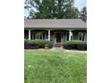 Inviting covered front porch with white pillars, trimmed hedges and ferns, enhancing the home's curb appeal at 12162 Mountain Laurel Dr, Roswell, GA 30075