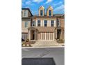 Three-story townhome exterior featuring a two car garage, with neutral colors and shutters at 118 Via Roma, Woodstock, GA 30188