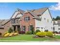 Charming two-story home with lush green lawn, manicured landscaping, and an attached two car garage at 431 La Perla Dr, Sugar Hill, GA 30518