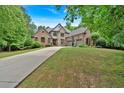 Beautiful brick home featuring a three-car garage, long driveway, and lush green lawn at 511 Etris Ct, Roswell, GA 30075