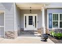 Close-up of front porch with stone accents, a white door with sidelights, and manicured landscaping at 1016 Buckeye Ln, Villa Rica, GA 30180