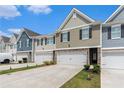Townhomes with attached garages, well-manicured lawns, and concrete driveway on a sunny day at 11730 Chatham Dr, Hampton, GA 30228