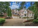Impressive brick home featuring mature trees, a three-car garage, and ample parking space at 8630 Moor Park Run, Duluth, GA 30097