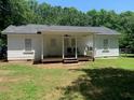Rear exterior view of the house showcasing a covered porch and a well-kept lawn at 106 E Wade St, Oxford, GA 30054