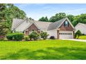 Charming home with well-manicured lawn, brick accents, a green door, and a two-car garage at 1978 Elmwood Cir, Snellville, GA 30078