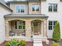 Charming stone-covered front porch with seating area and wooden front door at 3459 Clubland Dr, Marietta, GA 30068