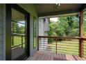 Covered porch featuring wood floors, metal railing, and a view of the lush greenery surrounding the property at 3427 Mill Stream Sw Ln, Marietta, GA 30060