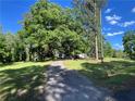 Long driveway leading to a charming home nestled among mature trees and a lush green lawn at 6675 Millwood Rd, Cumming, GA 30041
