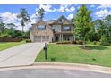 Beautiful two-story home showcasing lush front lawn, mature trees, and brick and stone facade at 3483 Addilyn Ne Ct, Marietta, GA 30066