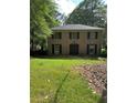 Traditional brick home featuring symmetrical design, well-kept lawn, and mature trees at 2315 Hudson Sw Dr, Lilburn, GA 30047