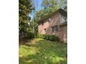 View of the side of a brick home, showcasing the lawn and simple landscaping at 2315 Hudson Sw Dr, Lilburn, GA 30047