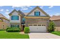 Two-story home with manicured lawn, brick accents, two-car garage, and a pathway to the front door at 2185 Creole Cir, Cumming, GA 30040