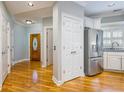 Hallway featuring gleaming hardwood floors, white trim, and a stainless steel refrigerator at 8650 Hope Mews Ct, Sandy Springs, GA 30350