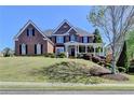 Beautiful brick home with a covered porch, well-manicured lawn, and mature trees at 2123 Floral Ridge Dr, Dacula, GA 30019