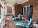 Relaxing front porch with striped lounge chairs, brick flooring, and charming decor at 2123 Floral Ridge Dr, Dacula, GA 30019