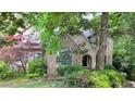 Charming home featuring a stone facade, arched entry, dormer windows, and lush, mature landscaping at 5357 Steeple Chase, Douglasville, GA 30135