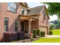 Attractive brick home featuring a covered front porch, manicured shrubbery, and a two-car garage at 6175 Beaver Crossing Dr, Cumming, GA 30040