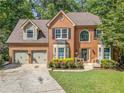 Traditional brick home boasts a well-kept lawn and an attached two-car garage at 1313 Cobblestone Ln, Woodstock, GA 30189
