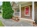 Inviting front porch of stone house with red door, white railing, and charming flower pots at 2004 Spicers Ln, Woodstock, GA 30189