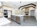 Modern kitchen featuring a large island, stainless steel appliances, and a fireplace with exposed beams at 2117 Ella Springs Dr, Covington, GA 30014