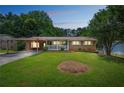 Evening view of a cozy brick home with a covered porch and carport, set against a backdrop of mature trees at 1526 Tanglewood Nw Way, Conyers, GA 30012
