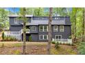 Modern two-story home with dark siding, white trim, and a deck nestled among trees at 510 Watergate Ct, Roswell, GA 30076