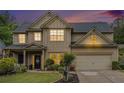 Charming two-story home featuring manicured lawn, neutral siding, a dark roof, and an attached two-car garage at dusk at 230 Haleys Ct, Woodstock, GA 30188