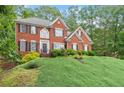 Two-story red brick home with black shutters and landscaped yard on a sunny day at 9048 River Bend Ct, Villa Rica, GA 30180