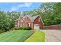 A beautiful two-story red brick home with a two-car garage and lush green lawn at 9048 River Bend Ct, Villa Rica, GA 30180