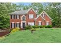 Two-story red brick home with black shutters and landscaped yard on a sunny day at 9048 River Bend Ct, Villa Rica, GA 30180