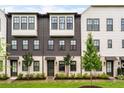 Attractive townhome exterior with a mix of white brick and dark wood, accented by young trees at 6635 Beacon Dr, Atlanta, GA 30328