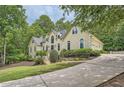 An elegant home nestled among lush trees, showcasing a multi-car garage and circular driveway at 5940 Plantation Dr, Roswell, GA 30075