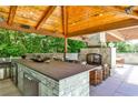 Outdoor kitchen featuring stainless steel appliances, stone fireplace and wood ceiling at 4309 Sentinel Post Nw Rd, Atlanta, GA 30327
