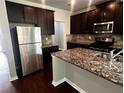 Kitchen boasts dark wood cabinets, stainless steel appliances, and granite countertops at 2363 Bear Mountain St, Lithonia, GA 30058