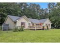 Rear exterior featuring a spacious fenced in yard and a beautiful wooden deck with an umbrella and stairs at 4746 Mulberry Rock Rd, Dallas, GA 30157