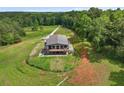 Aerial view of modern farmhouse on acreage, showcasing large deck and surrounding wooded land at 1971 Centennial Rd, Rutledge, GA 30663