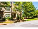 Brick townhouse with covered front door entrance, landscaping, and mature trees at 1420 Baygreen Rd, Suwanee, GA 30024