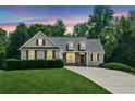 Charming home at dusk featuring a manicured lawn, mature trees, and a welcoming facade at 6890 Autumn Hills Dr, Cumming, GA 30028