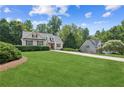 Charming home with a lush green lawn, mature trees, and a long driveway at 6890 Autumn Hills Dr, Cumming, GA 30028