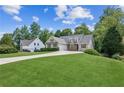 Charming home with a lush green lawn, mature trees, and a long driveway at 6890 Autumn Hills Dr, Cumming, GA 30028